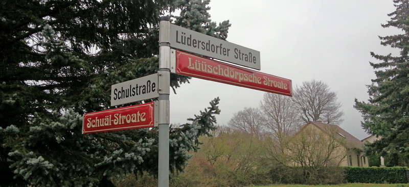 Zu sehen sind Straßenschilder mit plattdeutscher Übersetzung der Straßennamen