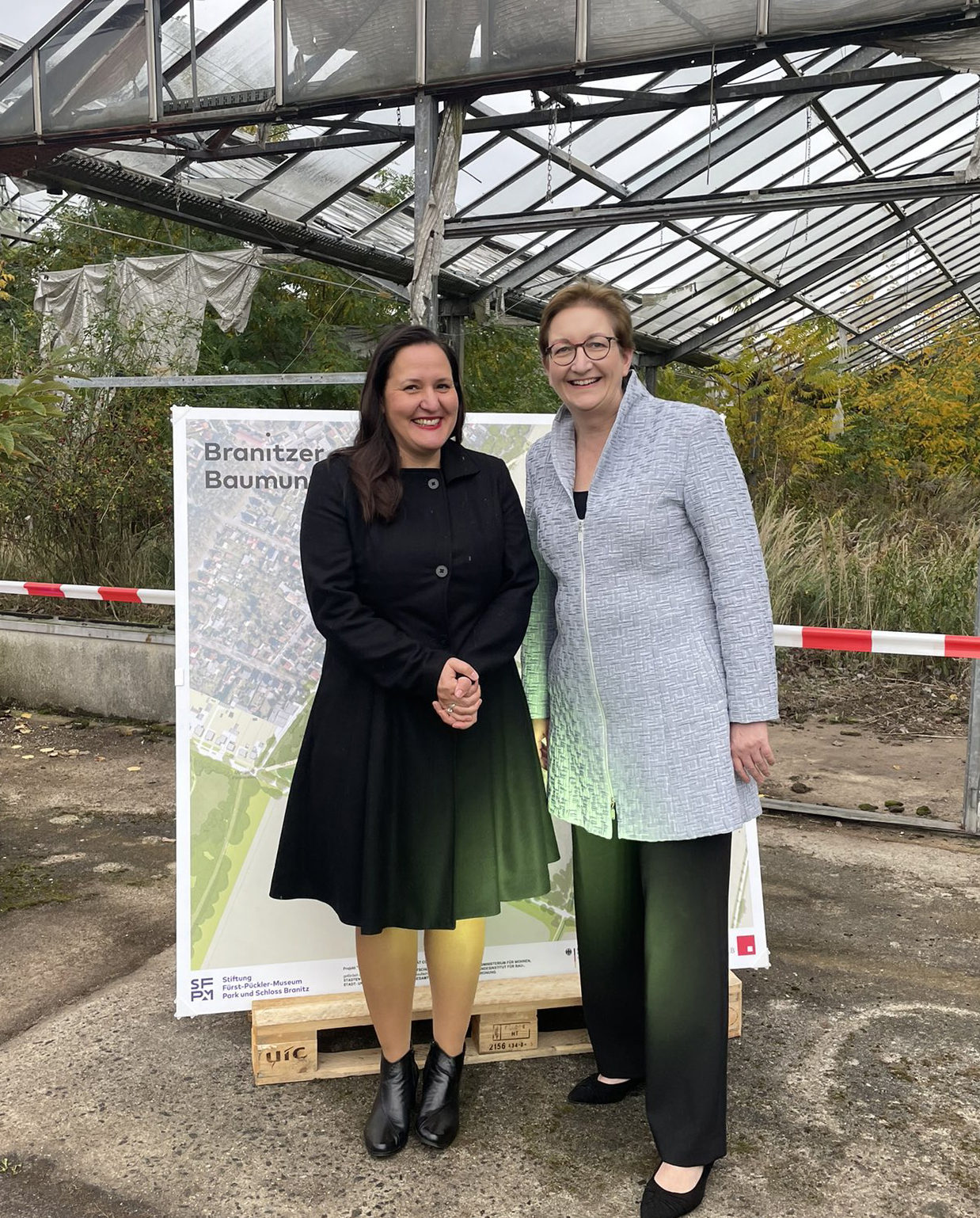 Ministerin Manja Schüle und Bauministerin Klara Geywitz stehen vor einem Gewächshaus