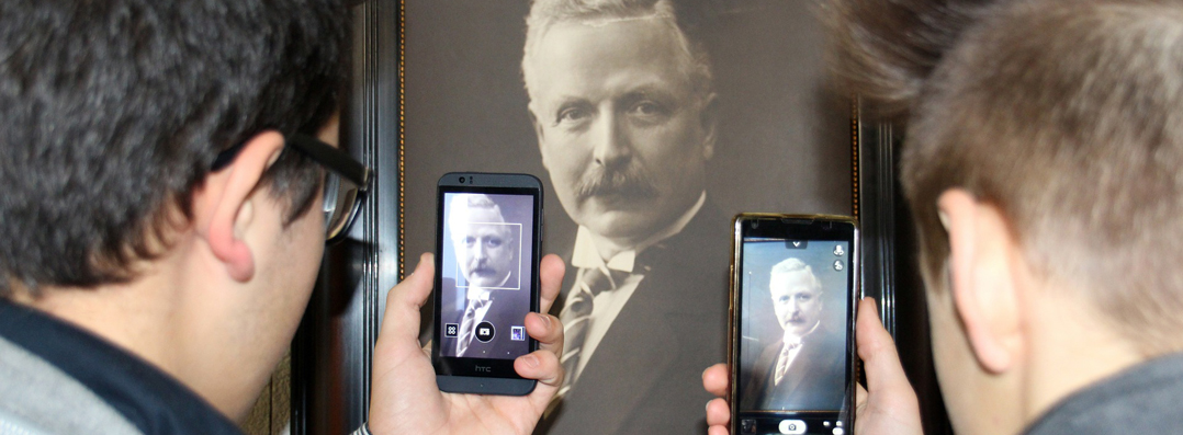 2 junge Männer fotografieren ein Porträt Bild mit ihren Smartphones ab. 