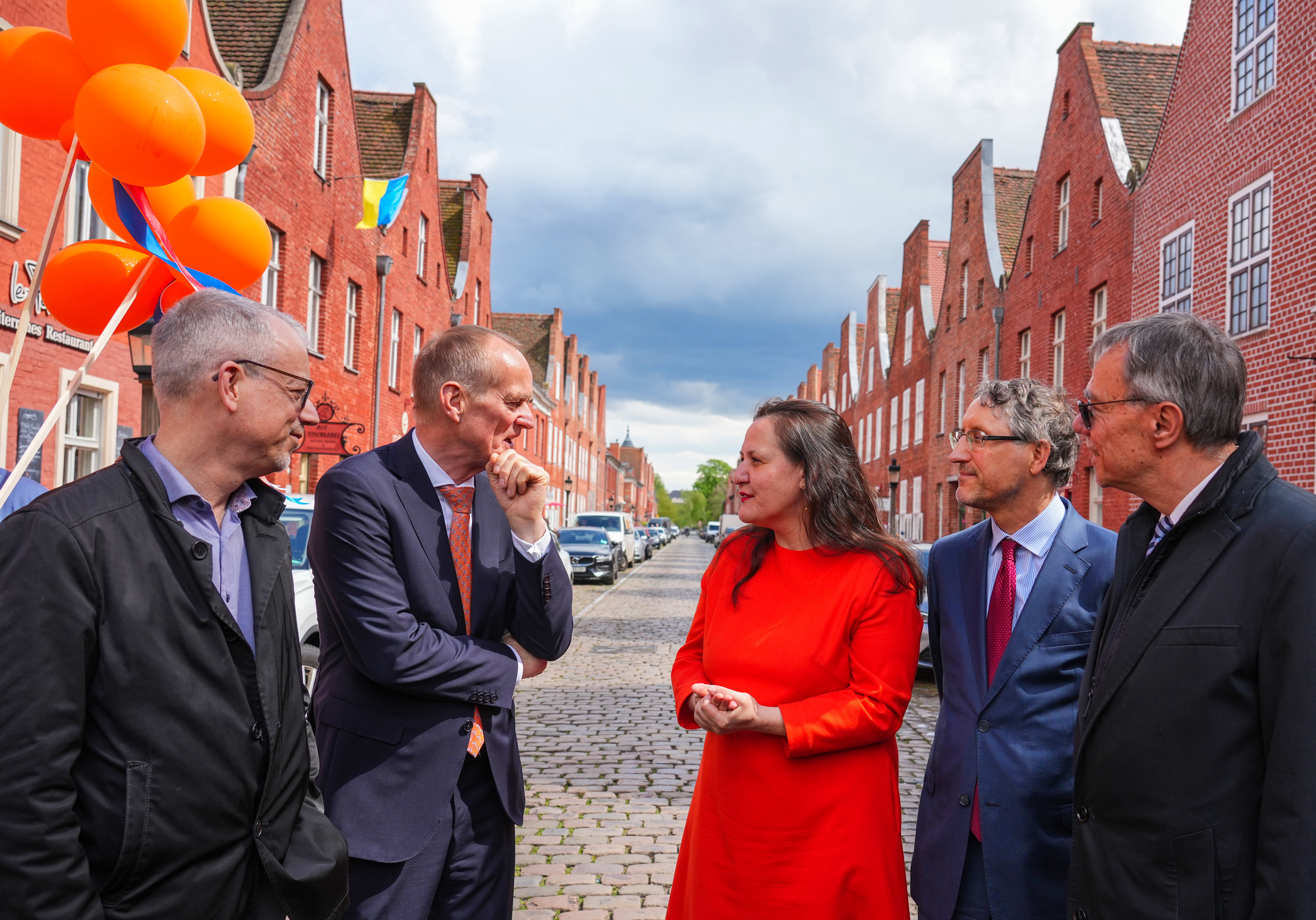 Zu sehen ist Kulturministerin Manja Schüle in einem orangenen Kleid im Gespräch mit dem Botschafter des Königreichs Niederlande in Deutschland,  Ronald van Roeden