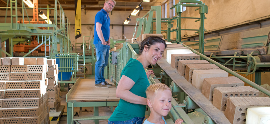 Bild: Eine Frau, ein Mann und ein Kind besichtigen die Setzerhalle im Ziegeleipark Mildenberg