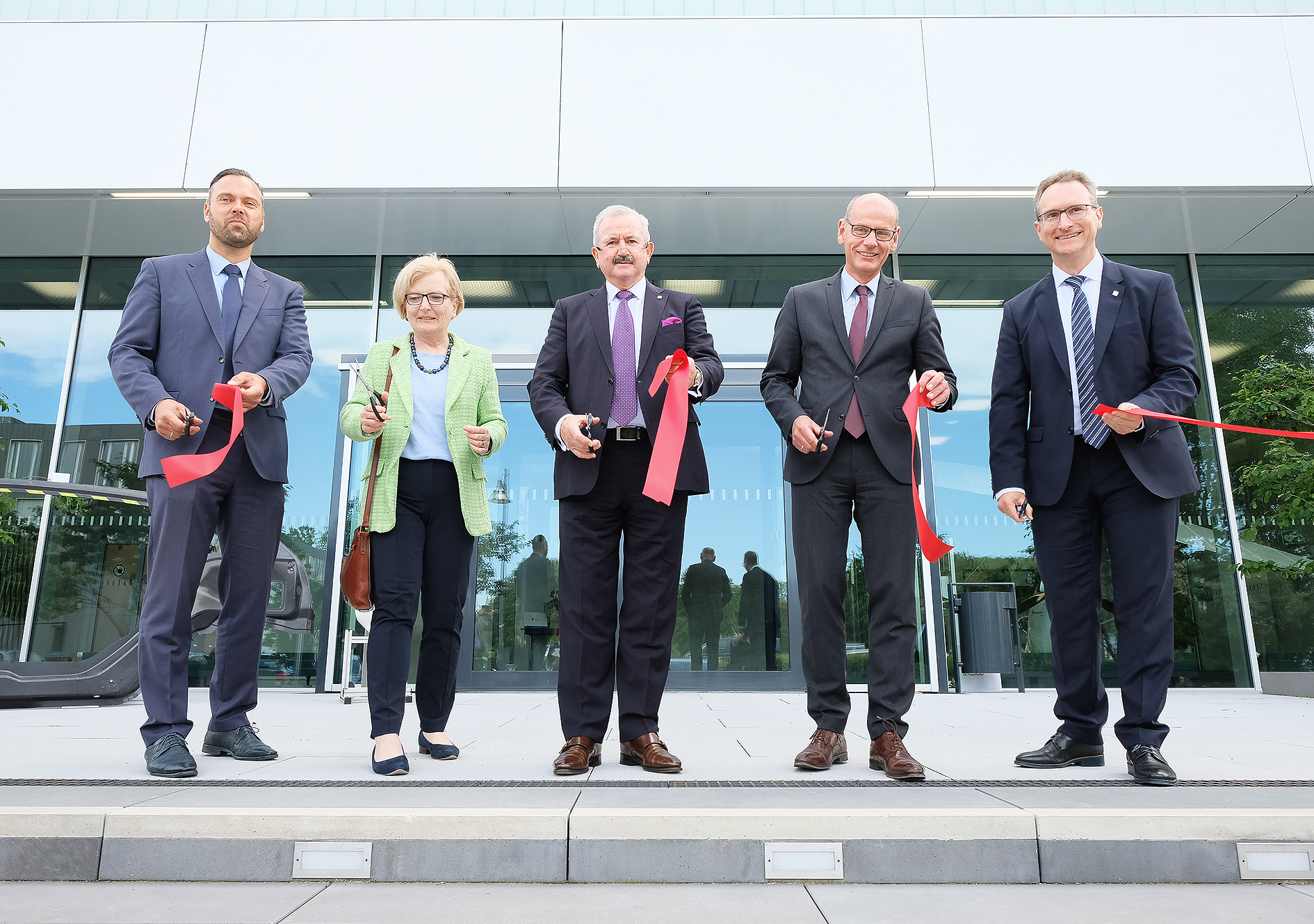 Die Akteure vor dem neuen Gebäude mit durchschnittenem Band